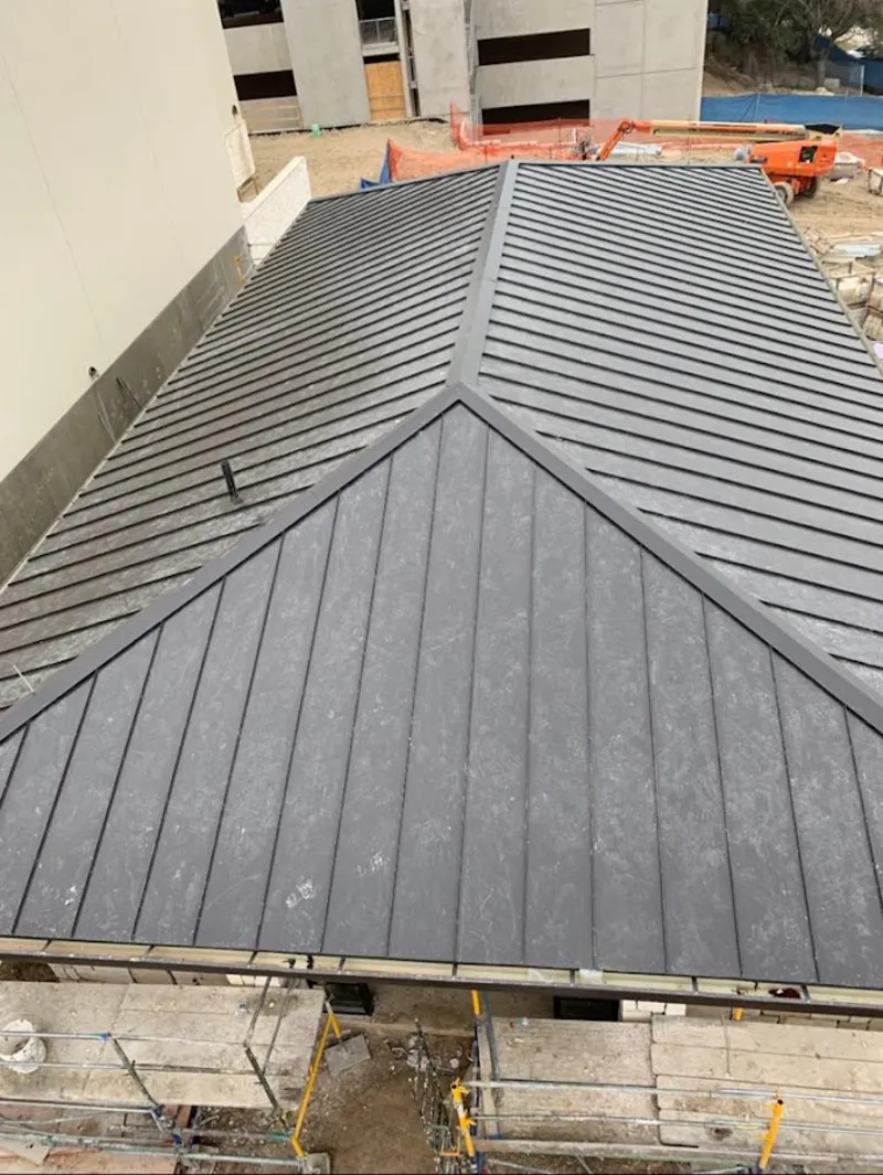 Commercial metal roof construction with crane equipment in Logan